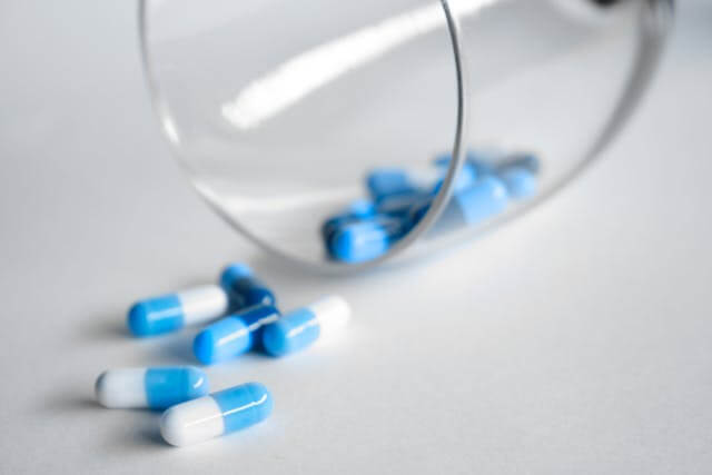 blue and white pills spilling from a bottle