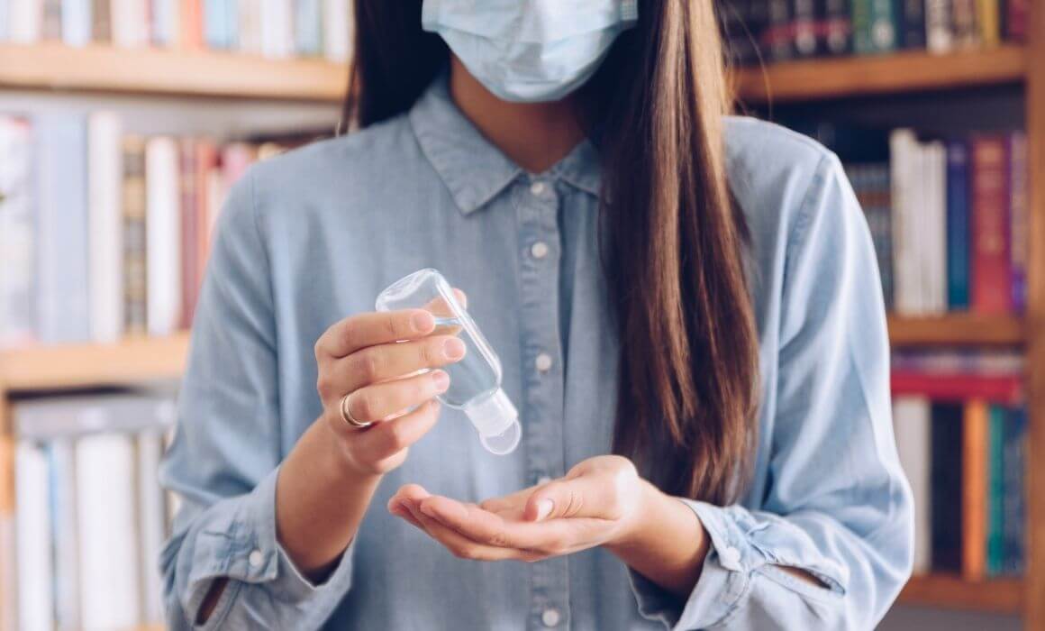 Person wearing mask and using hand sanitizer